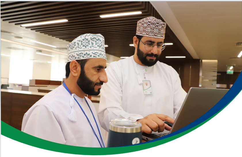 Two OETC colleagues reviewing work on a laptop in the office
