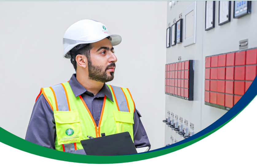 OETC engineer in safety gear inspecting a substation control panel